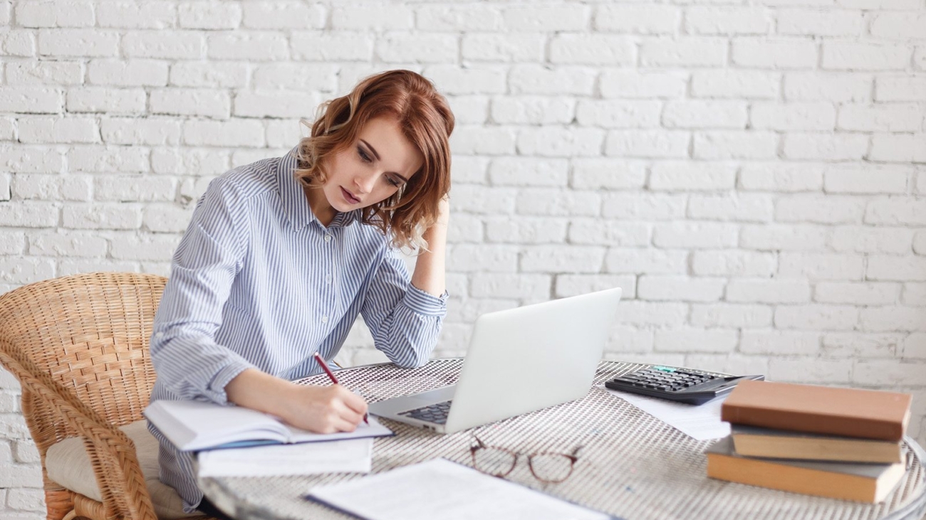 Woman freelancer female hands with pen writing on notebook at home or office